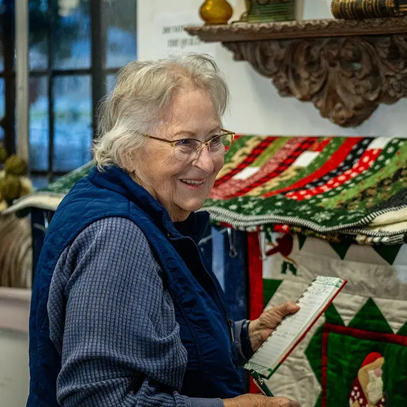 Woman smiling next to quilts